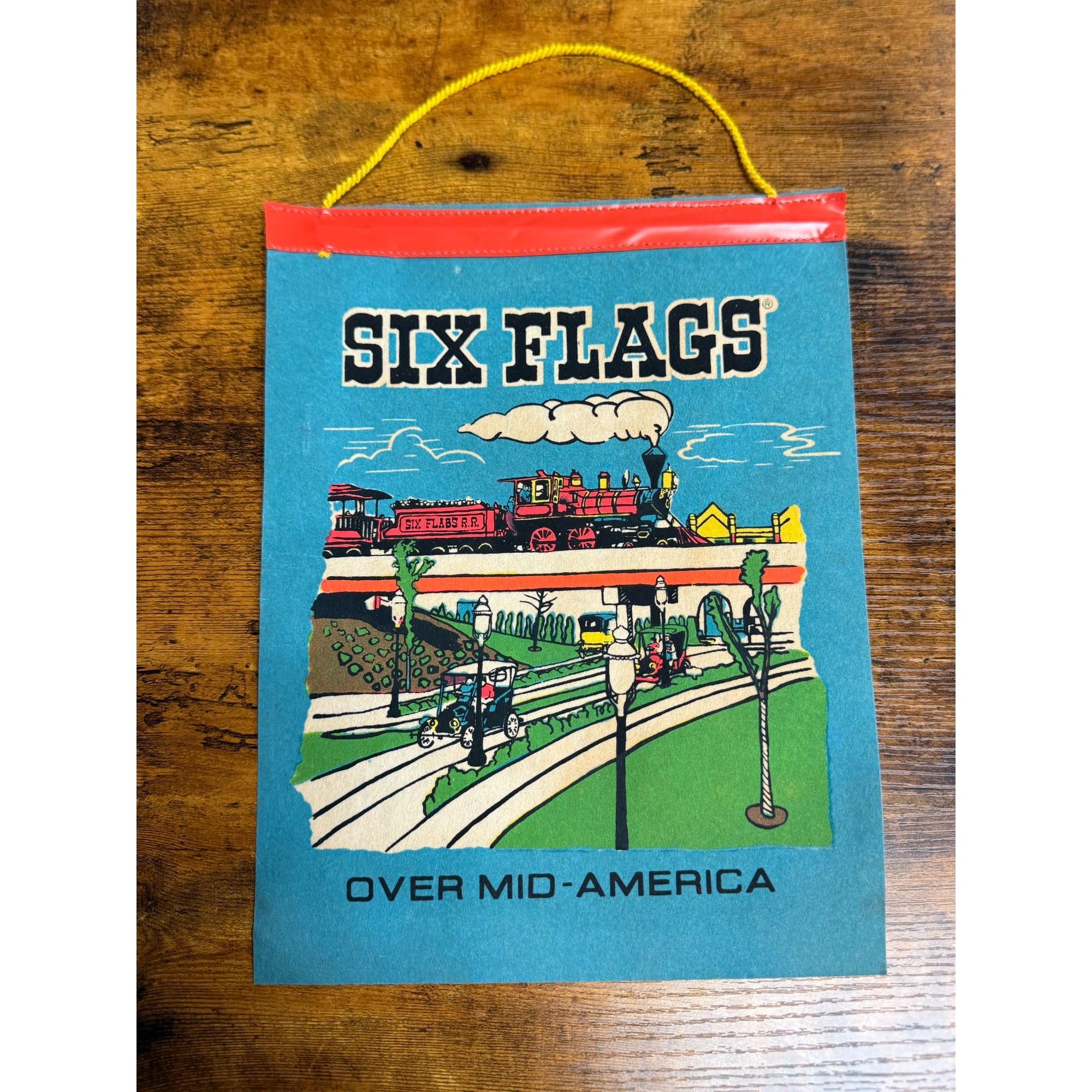 Vintage Six Flags Over Mid-America Hanging Souvenir Colorful Train & Park Scene On Blue Background With Yellow Cord